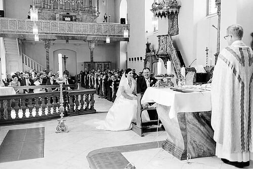 Brautpaar läuft samt Blumenmädchen lachend aus der Kirche